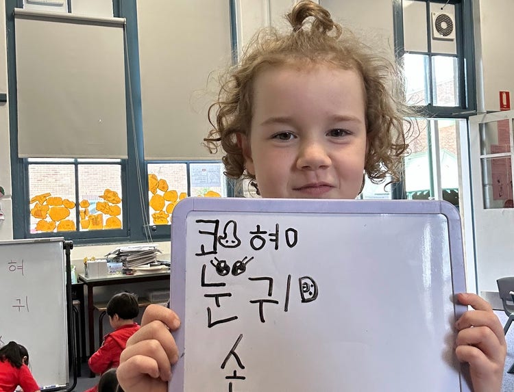Student holding mini whiteboard with Korean letters